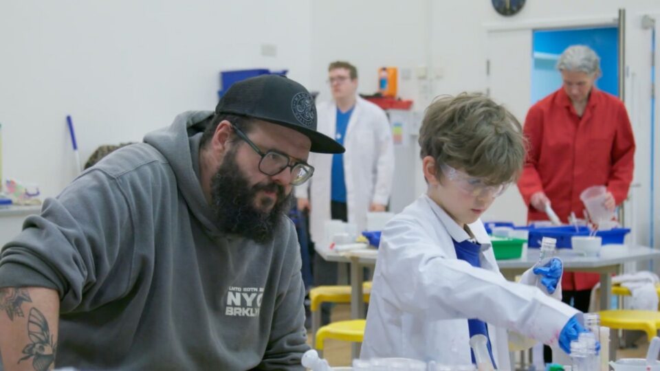 man with child teaching science in lap